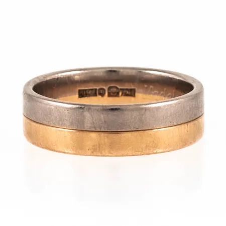 Slät ring i 18K röd- och vitguld. Den är i storlek 18¼, är 6 mm bred, 1,5 mm hög och väger 7,9g. Stämplad JML, 18K & kattfot. Bruksslitage, gravyr.