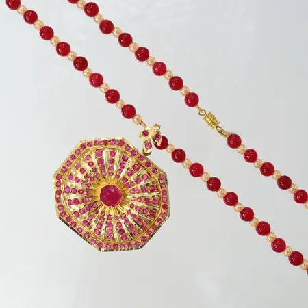 Collier med kulor samt integrera hänge, hänge troligen syntetiska rosa safirer, längd 49cm, bredd ca 4,5-6mm, hänge 55x65mm, bör träs om, ostämplade, 21K, bruttovikt: 35,3g.