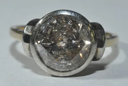 Solitär med 1 diamant på 3,40ct något gammalslipad 10,2 x 10,2 x 5,3 mm. Något brun. Piqué 3. Hack i rodisten och något stor kulett. Nyvärde 73000:- enligt Gemologen. 14k 3,8 gr Ø 18 mm. Vikt: 3,8 g