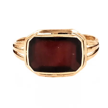 Ring i 18K guld med en mörkröd sten. Den är 2,5 - 10,8 mm bred, är i storlek 17½ och väger 3,5g. Vass i dekorranden på ena sidan.