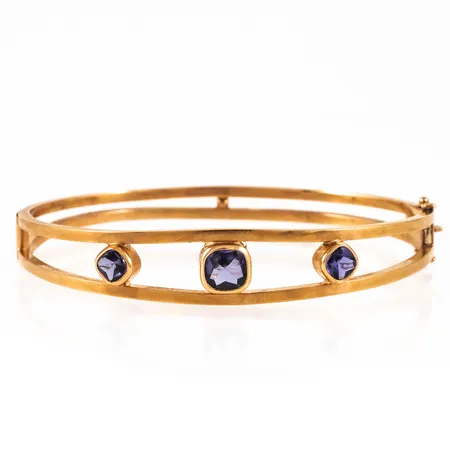 Armring i 18K guld med 3 ametister. Innermått c:a 17,5 cm, 62 x 49 mm, är 6 - 12 mm bred och väger 10,9g. Öppningsbar, kistlås. Stämplad K9 (1960), ESM (Svedboms Guldsmeds AB, Vetlanda), 18K & kattfot. Ojämnheter såsom små bucklor förekommer. Något skev.