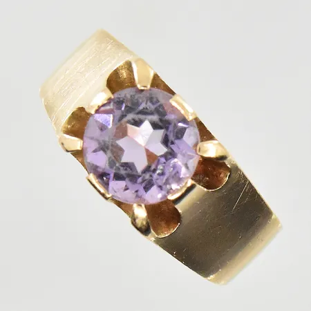 Ring med lila sten, stl 18¼, bredd 4-8 mm, ojämn skena, 18K. Vikt: 5,7 g