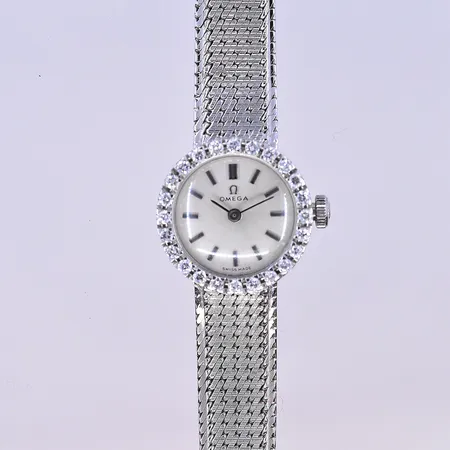 Damur Omega med diamanter i krans 24x0,01ct och integrerad länk, manuell, Ø18 mm, längd 18 cm, bredd länk 10 mm, vitguld, 18K. Bruttovikt 30,9g.