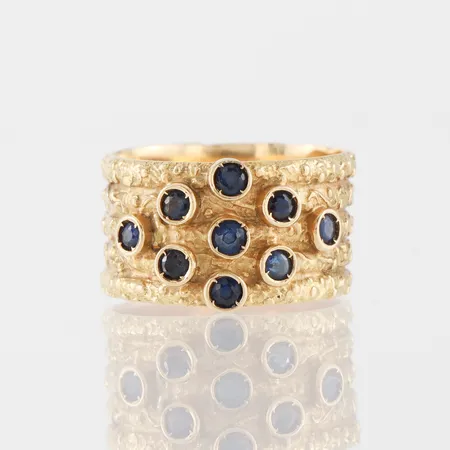Ring med 9 st små safirer,storlek 16 ½ mm, bredd 10.8 mm,18k. Vikt: 6,9 g