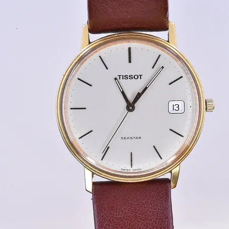 Herrur Tissot Seastar, quartz, datum, Ø34 mm, graverad boett, brunt läderband, 18K. Bruttovikt 28,8g.
