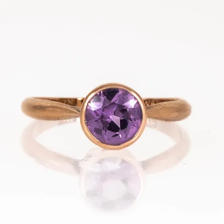 Ring i 14K med rosalila sten (sannolikt syntetisk safir). Den är i storlek 18, är 1,5 - 8 mm bred och väger 2,8g. Finska stämplar V6 (1950). Enstaka naggar på fasetterna men fin lyster ändå. Gravyr initialer.