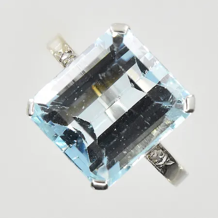 Ring med blå sten och vita stenar, stl 17¼, bredd 2-12 mm, flertalet nagg på mittsten, vitguld, 18K. Vikt: 3,9 g