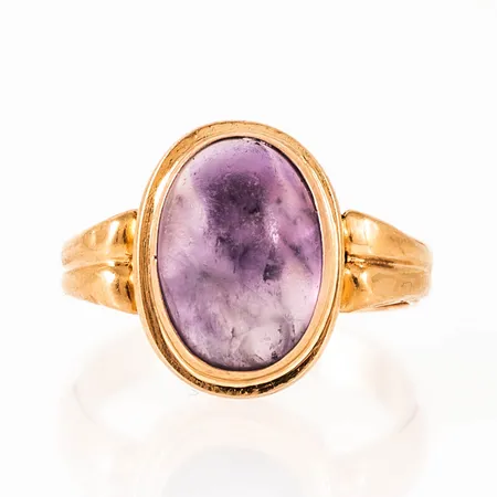 Ring i 18K guld med en cabochonslipad ametist (matt). Den är 3,6 - 16,4 mm bred, är i storlek 18 och väger 5,1g. Något oval skena. 