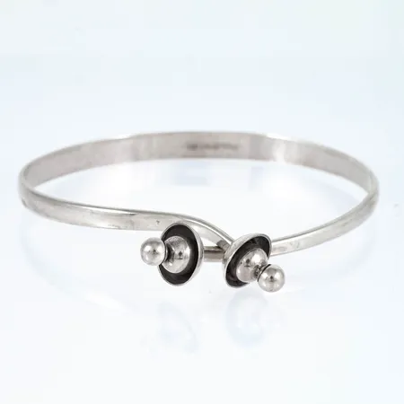 Armring i silver. Det är 4 - 6 mm brett, innermått 19,5cm och väger 15,5g. Öppningsbar. Stämplad Q9 (1966), KHM (H.Michelsson Eftr AB, Stockholm), silver, kattfot. 