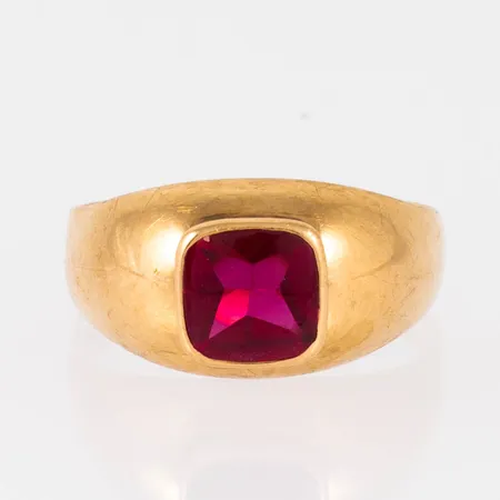 Doserad ring i 18K guld med röd syntetisk spinell. Den är i storlek 17¼, är 3 - 10 mm bred och väger 2,8g. 18K, kattfot. 