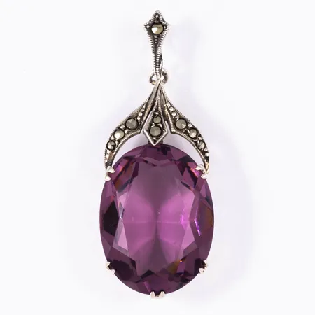 Hänge i silver (830/1000) med lila sten och markasiter. Det är 15 mm brett, 39 mm långt inkl. ögla och väger 6,3g. 