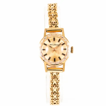 Damur Belinda i 18K guld med 18K band. Boett Ø 18,5 mm. Manuellt verk. Safirglas. Totallängd 16,5 cm. Bandet är 5,7 mm brett och har kistlås. Totalvikt 18,2g.