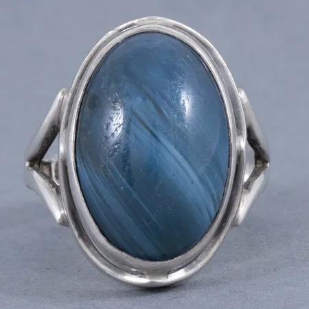 Ring i silver med blå slaggsten 17,5 x 12 mm. Den är i storlek 16½, är 3 - 20 mm bred och väger 5,7g. Stämplad O9 (1964), MVL (Märta Lindgren Silver & Guld, Lindesberg), silver, kattfot. Repig sten. 