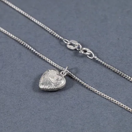 Kedja pansar samt ett mönstrat hjärta i silver (925/1000). Kedjan är 36 cm lång, 1,3 mm bred och har springring. Hjärtat är 16,5 mm långt inkl. ögla. De väger 2,9g tillsammans.