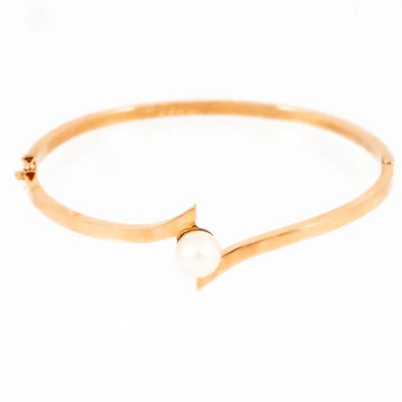 Stelt armband i 18K guld med en 7,5 mm´s odlad pärla. Det är 2,7 - 15,2 mm brett, har ett innermått på 18 cm och väger 7,3g. Kistlås. Namngravyr på insidan.
