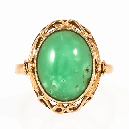 Umeåtillverkad ring i 18K guld med en cabochonslipad krysopras 14,5 x 11,5 mm. Den är i storlek 17¾, är 2,2 - 19 mm bred och väger 5,7g. Stämplad V7 (1923), JH (J. Hanson, Umeå), 18K och kattfot. Gravyr. 