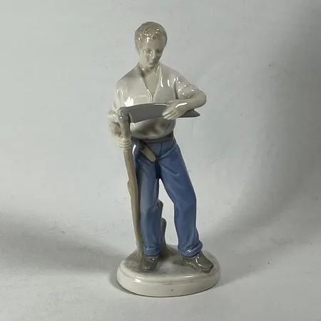 Porslinsfigurin, man med lie, höjd 24cm, något instabil på fot, Tyskland Skickas med paket.