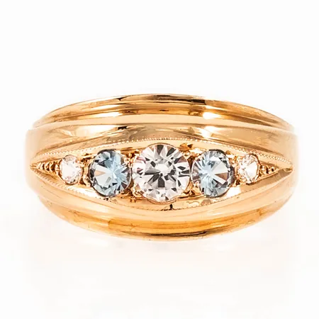 Ring i 18K guld med ljusblå och vita syntetiska spineller. Den är i storlek 18, är 3 - 10 mm bred och väger 2,9g. 