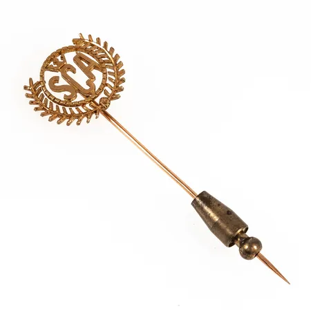 Nål SCA i 18K guld. Den är 19 mm bred, 61 mm lång och väger 2,7g. Stopp i metall medföljer. 