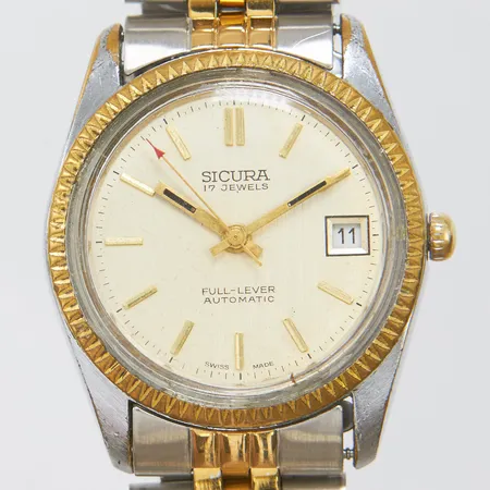 Herrur Sicura Full Lever stål automatisk 35,5mm, dag, inplastad stållänk, färgbortfall på boett, mycket slitage, inga tillbehör. 