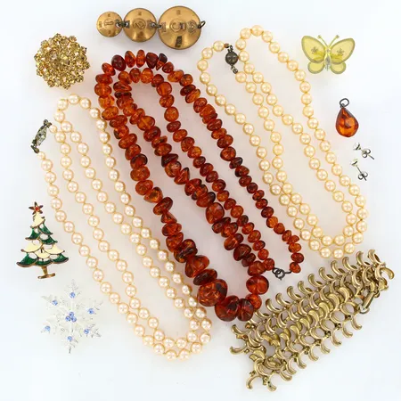 Två pärlcollier med plastpärlor varav ett med silverlås, ett collier i gulmetall, ett collier samt hänge i trolig bärnsten, fem broscher samt ett par örhängen i metall