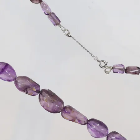 Collier med lila stenar troligen ametister längd 45cm bredd 4--12mm, ställvist hårt slitage, spår av säkerhetskedja men borttagen, lås i silver 935/1000 Vikt: 51,3 g