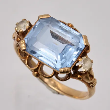 Ring i 18K guld, stl 17½, bredd 2-14,5mm, 1st blå sten, mått 9,5x11,6mm, 2st vita stenar, mått Ø3mm, tillverkad av John Petterssons Eftr Juvelerar Ab, år 1950, bruttovikt 5,33g, ca nettovikt 3,9g.