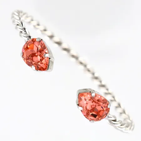 Armring Caroline Svedbom tvinnad rosa stenar ca 60x50mm, bredd 4-10 mm, mässing med rhodiumplätering, smärre skevhet.