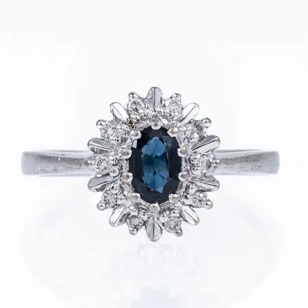 Carmoséring Guldfynd med en blå safir 6x4mm och 10 briljantslipade diamanter totalt 0,10ct, stl:18, bredd 2-12mm vitguld 18K 3,6g. 