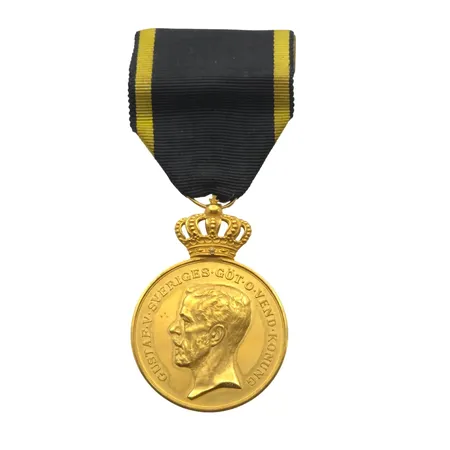 Guldmedalj "FÖR TROHET OCH FLIT" PRO PATRIA, Gustaf V, 23 K guld (krona i 18K guld), Ø33,5 mm, namngravyr på kantrand, bruttovikt inkl. band 34,6g Vikt: 34,6 g