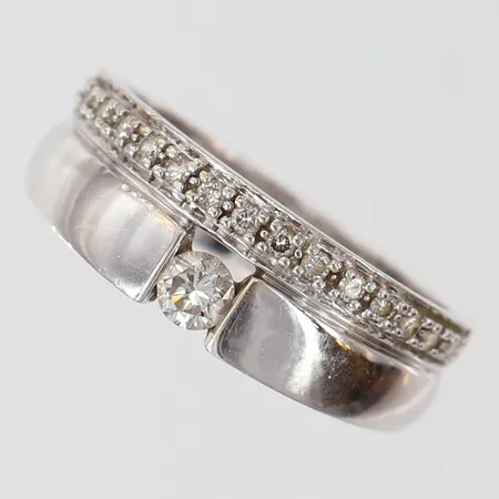 Ring med diamanter 1 x 0,15ct, 15 x 0,01ct, stl:17½, bredd 4,5-7mm, GHA, vitguld 18K.  Vikt: 5,6 g