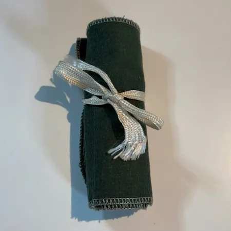 Besticklinda plats för 12 dessertbestick, grön filt, vita band.