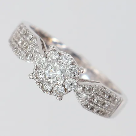 Ring med briljantslipade diamanter 1 x 0,15ct 8 x 0,03ct 36 x 0,01ct totalt ca 0,75ctv stl:17½ bredd 2,7-6,5mm gravyr vitguld 18K. Vikt: 3,7 g