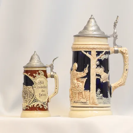 2 st Ölstop i keramik och lock i tenn Tyskland 1900-tal signerat Jägerlatein höjd 22 cm samt 14 cm (lagat)  Skickas med paket.