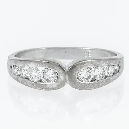 Ring med 8 briljantslipade diamanter totalt ca 0,60ct, stl:18, bredd 2,3-5,5mm, två stenar som ligger mot varandra har flisa borta från rondisten, enbart synbart med lupp. Vitguld 18K 4,5g. 