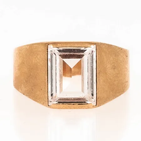 Ring i 18K guld med en vit syntetisk spinell. Den är 2,8 - 9,9 mm bred, stl:17 och väger 3,6g. Lite ojämn skena.