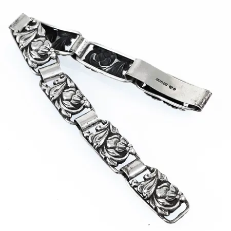 Armband i silver med blomsterdekor. Det är 19 cm långt, 11,6 mm brett och väger 16,0g. Kroklås. Svenska stämplar från 1952.