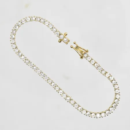 Armband med vita stenar längd 16½cm, bredd 3mm, ojämn länk, låser dåligt, 14K. Vikt: 10,7 g