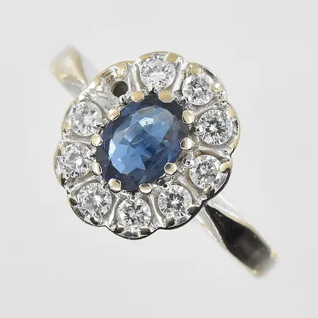 Ring med safir samt diamanter 9x0,05ct GFAB stl:18, bredd 3-13mm, en diamant saknas, slitna klor, vitguld, 18K. Vikt: 5,3 g