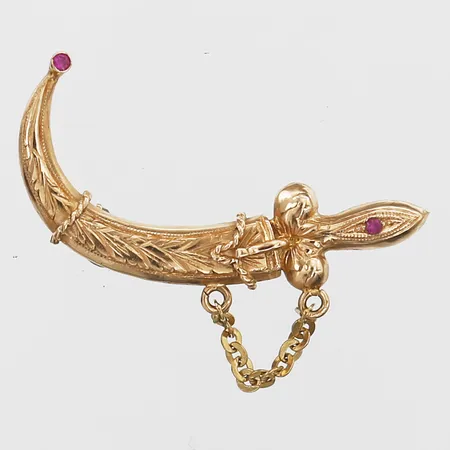 Brosch i form av en dolk med syntetiska rubiner, rörlig del, höjd: 40 mm, bredd: 14 mm, 18K guld. Vikt: 5 g