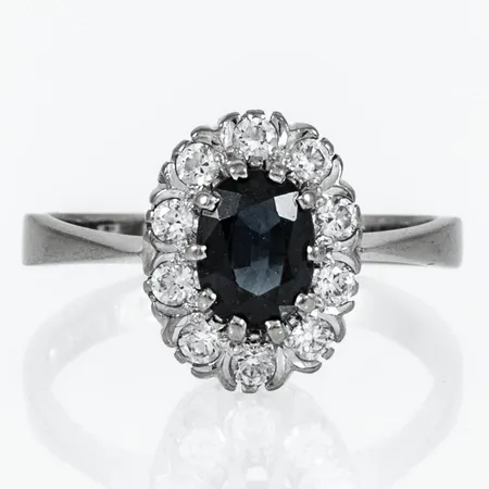 Carmoséring med en blågrön safir 1,16ct och 10 vita stenar (cz), ca. stl:17, skev skena, sprucken skarv, vitguld 18K 4,3g. 