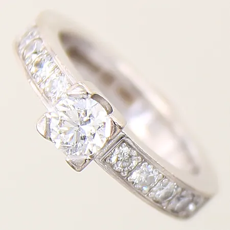 Ring med diamanter 1 x ca 0,50ct kvalitet W(H)/SI2 10 x ca 0,05ct, 3 indikerar på att vara syntetiska, stl:15½ bredd 3,4-5,5mm, gravyr, vitguld 18K Vikt: 7,2 g