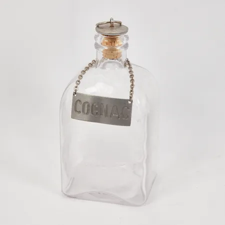 Brännvinsflaska med 1-öre myntpropp höjd 15cm, klarglas, flasketikett "Cognac" i vitmetall, bruksskick. 