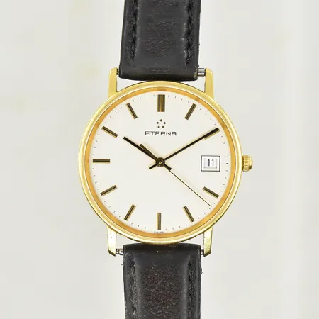 Herrur Eterna 18K quartzur, datum boett Ø34 mm, gravyr på boett, fungerade vid testtillfället, defekt läderband.