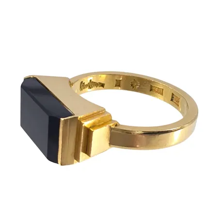 WIWEN NILSSON (1897-1974) LUND EXKLUSIV RING 18K guld, onyx, tidig tillverkning 1931 (E8), sidor med trappstegsformation, stl:18½ mm, skena bredd 3 mm, dekor mått 17,2x7,2 mm, uppbyggnad 6,5 mm, fint skick, något minimalt märke på sten (precis vid infästen) möjligen från tillverkning, stenens front helt utan anmärkning Vikt: 7,8 g