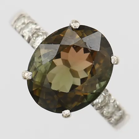 Ring med grönbrun turmalin ca 5,85ct samt briljantslipade diamanter totalt ca 0,30ct, stl: 17, 18K vitguld Vikt: 5,5 g