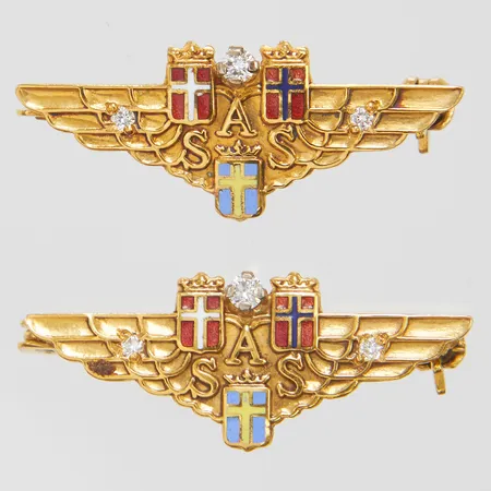 2 Broscher vingar med SAS emblem, 26,5x10,5mm, diamanter 2 x ca.0,03ct samt 4 x ca.0,01ct, emalj, personlig gravyr, 18K Vikt: 4,5 g