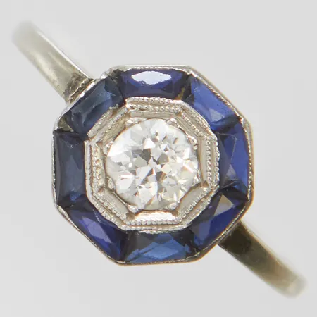 Ring med gammalslipad diamant 1 x ca.0,35ct, ca.TCr-Cr(I-J)/SI1 samt syntetiska safirer, stl: 17-, bredd: 1,3-9,5mm, liten spricka i fattningen, en safir mindre än övriga, ostämplad, skena i 14K vitguld, fattning i platina, bruttovikt 2,0g Vikt: 2 g
