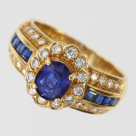 Ring med ovalslipad Safir 1,35ct carrèslipade safirer totalt 0,45ctv samt diamanter ca 12 x 0,02ct 20 x 0,01ct totalt 0,40ctv enligt gravyr stl:16½ bredd 3,8-11mm 18K.  Vikt: 6 g