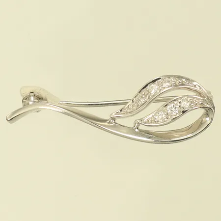 Brosch med diamanter 1 x ca 0,02ct, 5 x ca 0,01ct, längd 32mm, bredd 5-10mm, 18K, 2,4g Vikt: 2,4 g